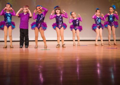 A group of young children wearing pink and blue outfits, standing together.